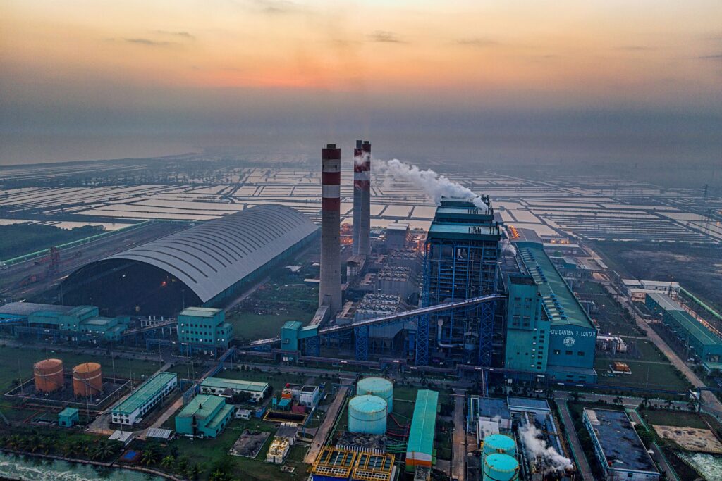 Aerial view of a power plant in Banten, Indonesia emitting smoke against a dusk sky.